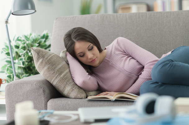 Girl reading a book on the sofa - Foto, imagen