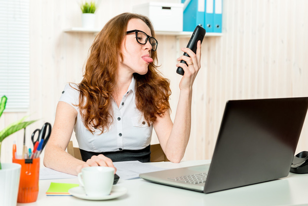 Cheerful business woman showing tongue interlocutor on the phone - Photo, Image