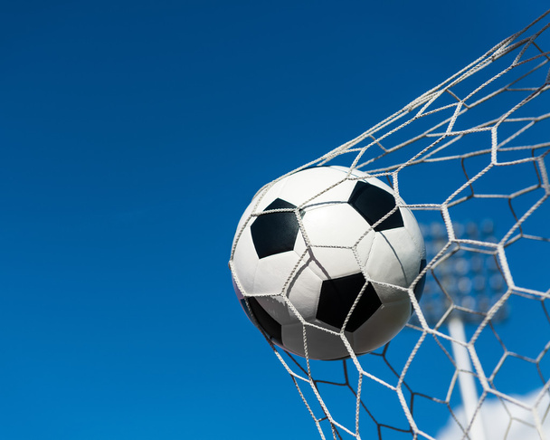voetbal in doel netto met blauwe hemel - Foto, afbeelding
