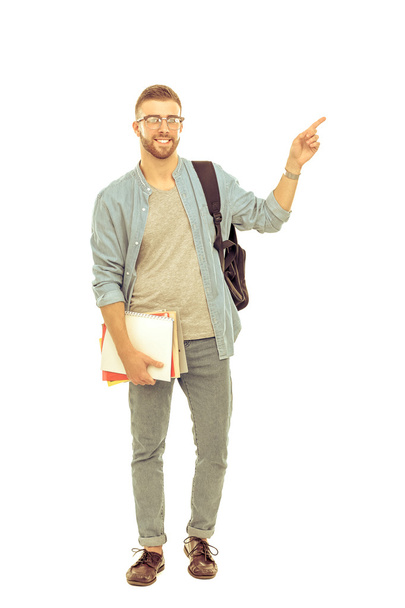 A male student with a school bag holding books and pointing isolated on white background - Foto, imagen