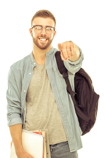 A male student with a school bag holding books and pointing you isolated on white background - Fotoğraf, Görsel