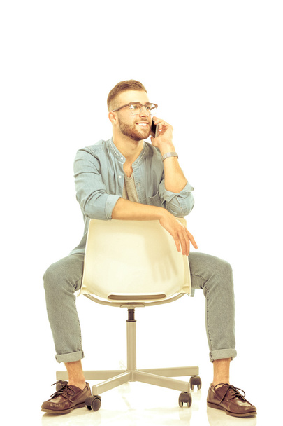 Young man sitting on chair and using mobile phone - Foto, Imagen