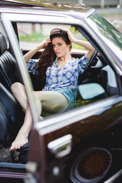 Brunette sitting in open car in summer, tinted photo - Foto, afbeelding