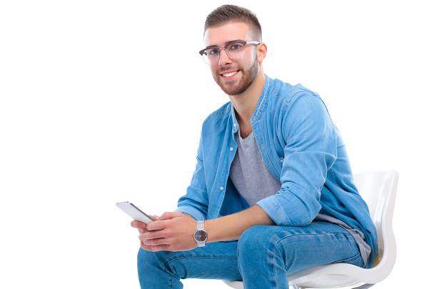 Young man sitting on chair and using mobile phone - Фото, изображение