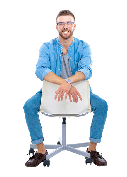 Fiatal ember ül a széken, elszigetelt fehér háttér felett - Fotó, kép