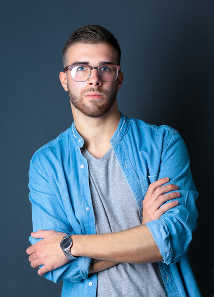 Portrait of a happy casual man standing isolated on a dark background - Foto, Imagem
