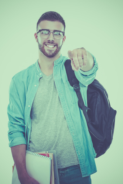 Ένας άνδρας των φοιτητών με τη σχολική τσάντα κρατώντας βιβλία και επισημαίνοντας σας απομονώνονται σε λευκό φόντο - Φωτογραφία, εικόνα