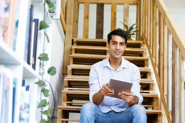 Portrait of young man sitting at the stairs in office - 写真・画像