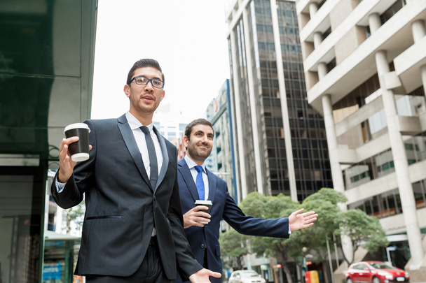 Two young businessmen hailing for a taxi - Фото, изображение