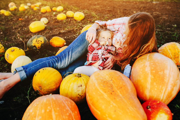 mother and daughter lie between pumpkins - Photo, Image