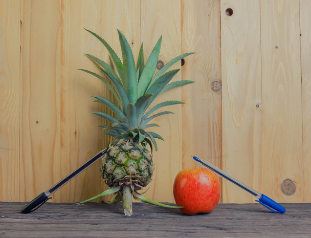 Kugelschreiber-Ananas-Apfel-Kugelschreiber auf Holzgrund. - Foto, Bild