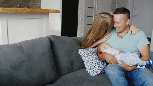 Una joven pareja riendo y sonriendo alegremente. Papá sostiene al bebé en sus brazos, son felices.
 - Imágenes, Vídeo