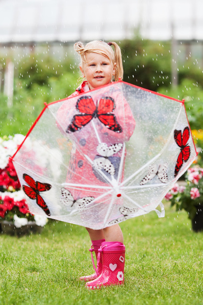 Серьезный задумчивый хорошенькая девочка в красном плаще с зонтиком ходить в парке летом
 - Фото, изображение