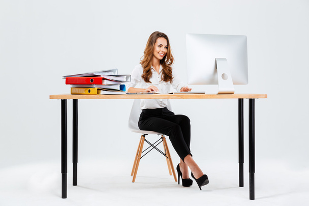 Beautiful happy businesswoman using computer while sitting at the desk - Foto, afbeelding