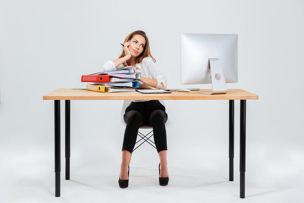 Full length portrait of businesswoman thinking about something holding pen - Foto, imagen