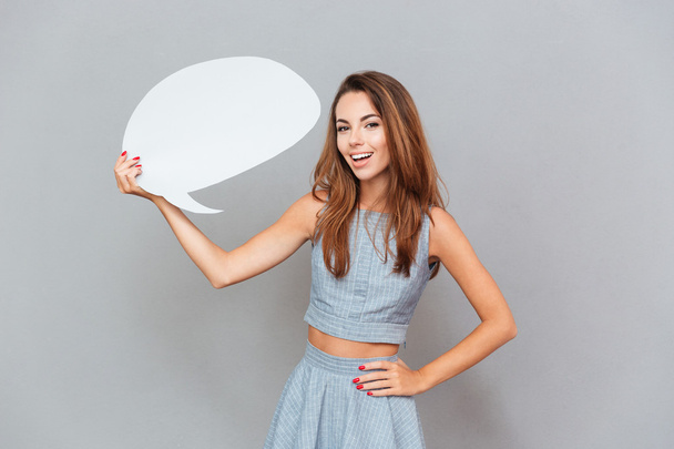 Cheerful attractive young woman standing and holding blank speech bubble - Φωτογραφία, εικόνα