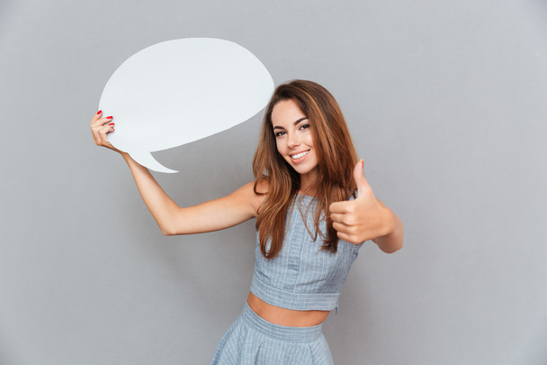 Happy woman holding blank speech bubble and showing thumbs up - 写真・画像