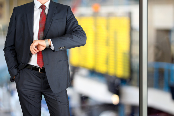 biznesmen sprawdzania czasu na swój zegarek na lotnisku - Zdjęcie, obraz