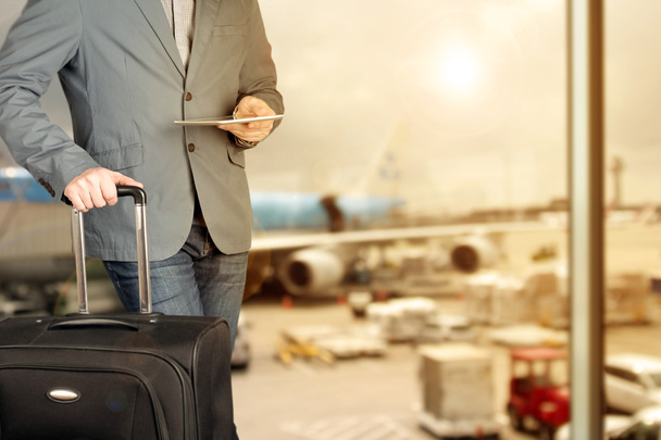 joven hombre de negocios utilizando tableta digital con equipaje en el aeropuerto
  - Foto, imagen
