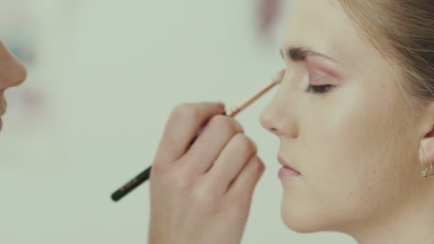 Make-up artist puts a brush for makeup to the eye model. - Felvétel, videó