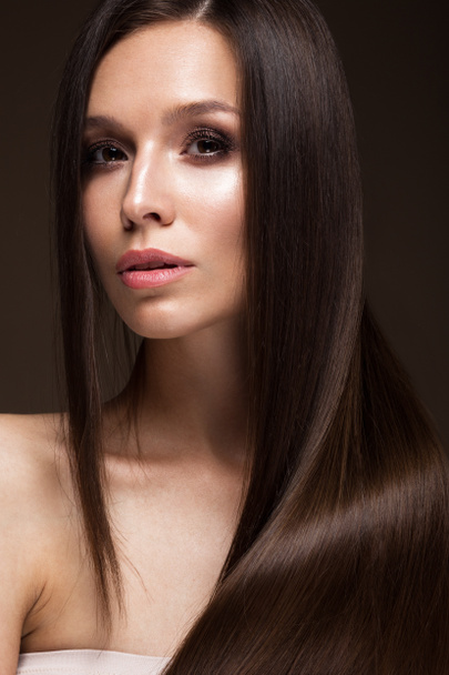 Beautiful brunette girl with a perfectly smooth hair, and classic make-up. Beauty face. - Foto, Bild
