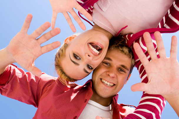 Young couple looking down with their heads together and having fun on beach - Foto, imagen