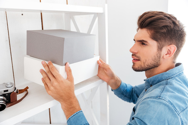 Hanadsome young man putting boxes on the shelf - Foto, Imagen