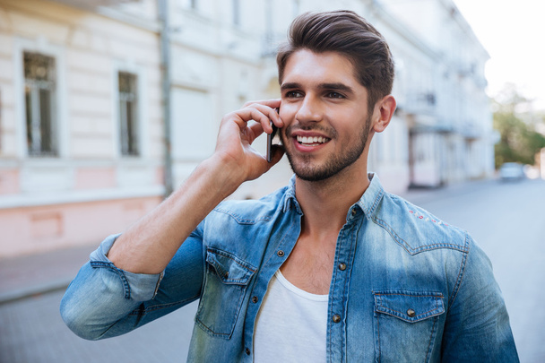 Happy man talking on cell phone outdoors - Fotoğraf, Görsel
