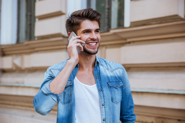 Smiling man standing on street and talking by cell phone - Photo, Image
