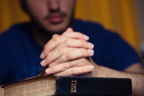 Young man praying on Bible - Фото, изображение