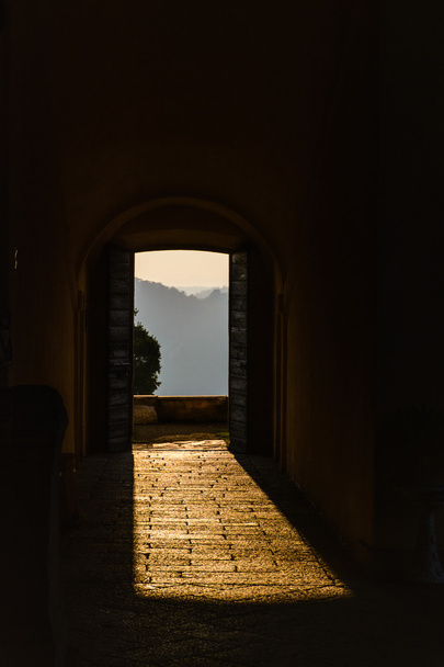 Door de open deuren in het zonlicht breekt een oude vesting. Italië, Angera. Kasteel Rocca di Angera. Toning - Foto, afbeelding