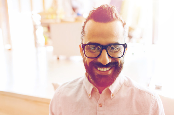 Χαμογελαστός άνθρωπος με γυαλιά και τα γένια στο γραφείο - Φωτογραφία, εικόνα