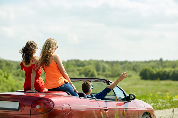 happy friends driving in cabriolet car at country - Foto, Imagen