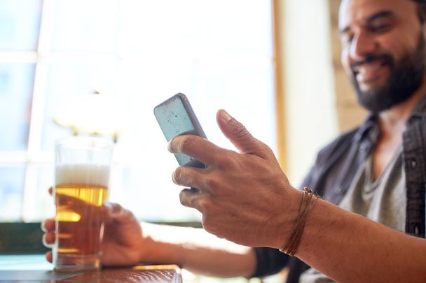 close up of man with smartphone and beer at pub - 写真・画像