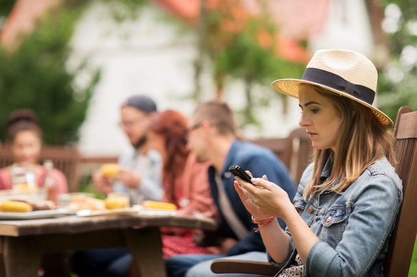 woman with smartphone and friends at summer party - Photo, image