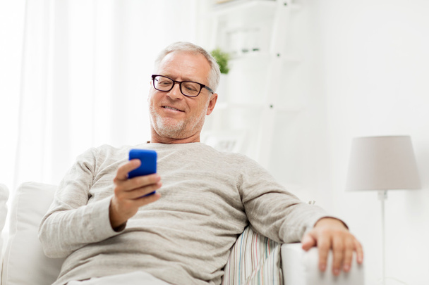 happy senior man texting on smartphone at home - Fotografie, Obrázek