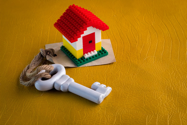 Μοντέλο πλαστικού σπιτιού με κλειδί και χαρτί ετικέτας  - Φωτογραφία, εικόνα