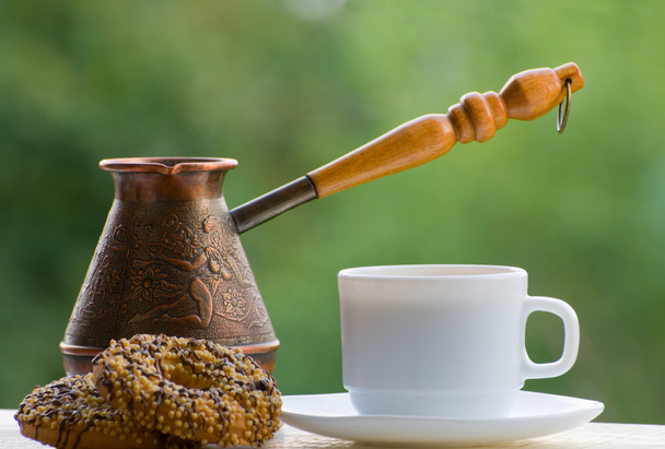 Mok koffie, koekjes en koperen potten buiten op groene achtergrond - Foto, afbeelding