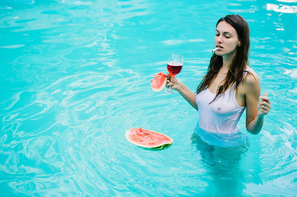girl smoking with watermelon and wine in pool - Photo, image