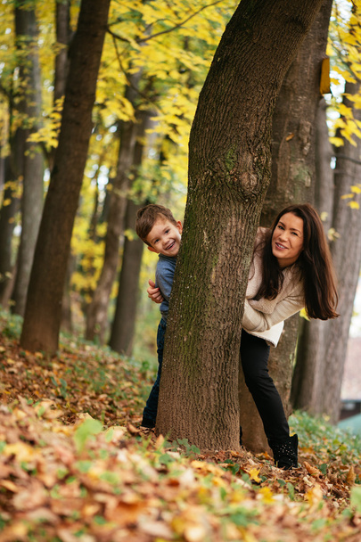 mother and son hiding behind tree - Foto, Bild