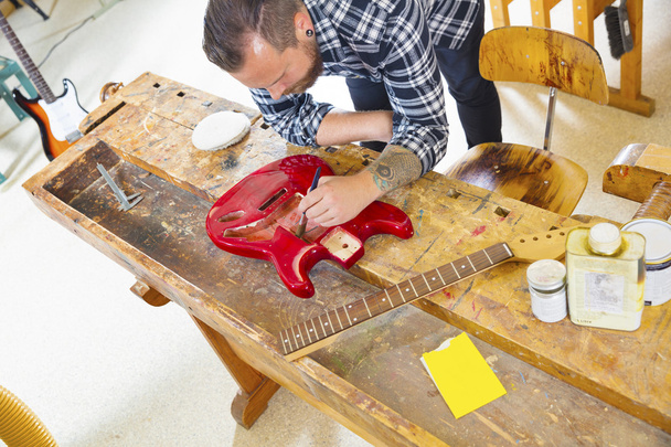 Artigiano che lavora in officina con una chitarra
 - Foto, immagini