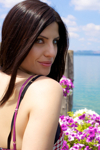 mooie vrouw die lacht op een meer met roze bloemen - Foto, afbeelding