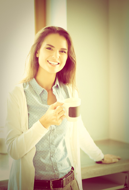 Happy woman drinking tea in the kitchen at home - Фото, изображение