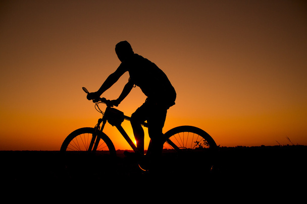 zonsondergang en silhouet achtergrondverlichting fietsers - Foto, afbeelding