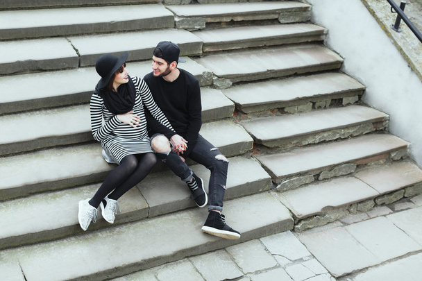 Man and pregnant girl sitting on stairs - Photo, image