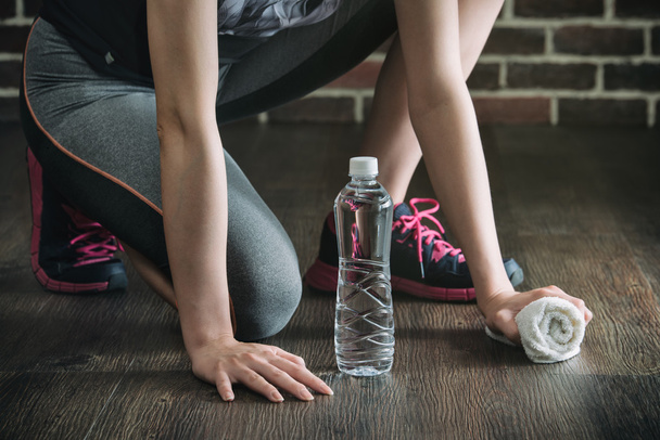 Squat on wooden floor take rest drinking water, fitness exercise - Fotó, kép