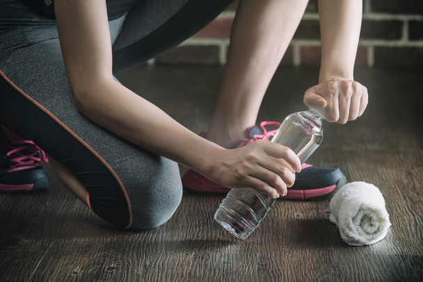 Squat on wooden floor take rest drinking water, fitness exercise - Valokuva, kuva