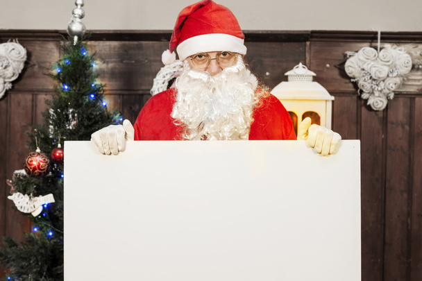 santa claus showing a blank billboard in her home - Photo, Image