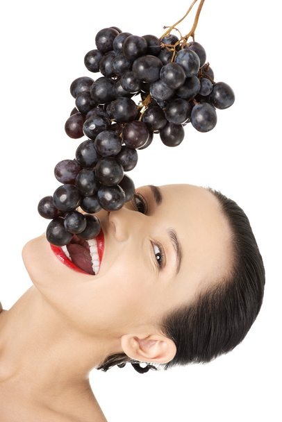 Beautiful sensual brunette eating grapes - 写真・画像