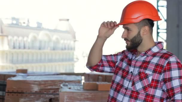 Férfi építő korrigálja kemény kalap az épület alatt - Felvétel, videó